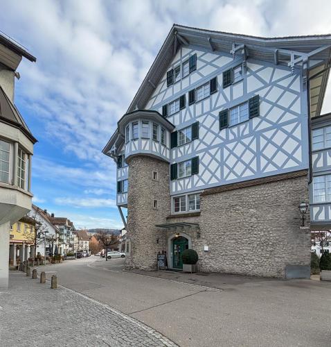 a white building with a clock tower on a street at Hotel und Restaurant zum goldenen Kopf in Bülach