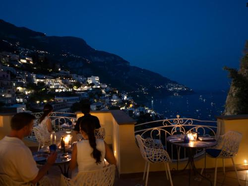 a group of people sitting at tables on a balcony at night at Hotel Posa Posa in Positano