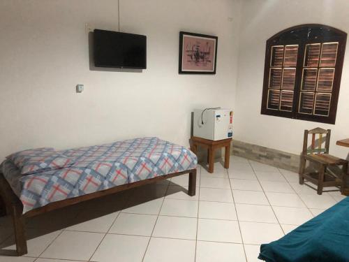 a bedroom with a bed and a tv on the wall at Pousada Robijn in Cabo de Santo Agostinho