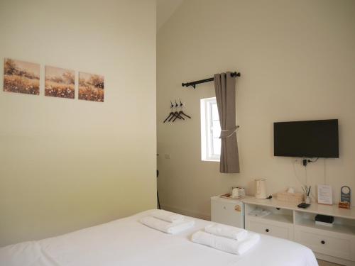 a bedroom with a white bed and a tv at Scholes Hill Khao Yai สกอลส์ ฮิลล์ เขาใหญ่ in Mu Si