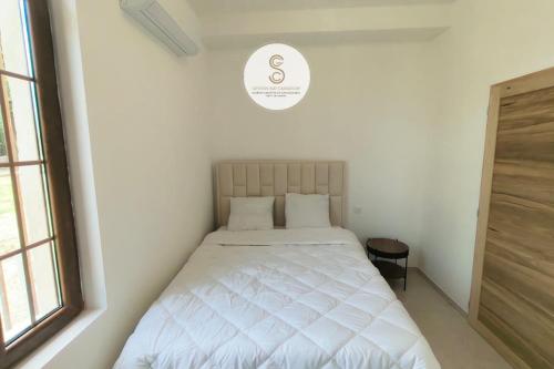 a white bed in a white room with a window at Mas Batelle 2 Arles in Arles
