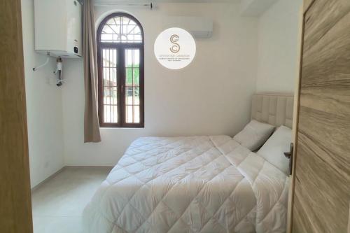 a white bedroom with a bed and a window at Mas Batelle 2 Arles in Arles