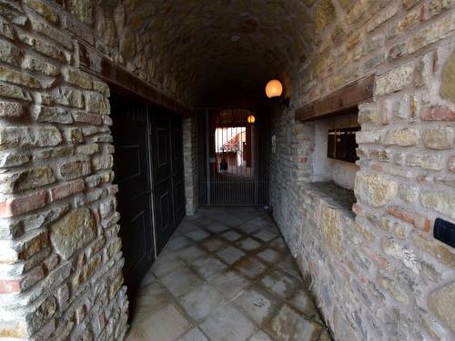 an alley with a brick wall and a black door at Hillview Langhe Apartment in Belvedere Langhe