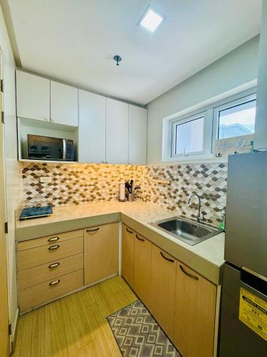 a kitchen with white cabinets and a sink and a window at 1BR Hotel Vibe Condo FULLY FURNISHED Trees Residences near SM Fairview in Manila