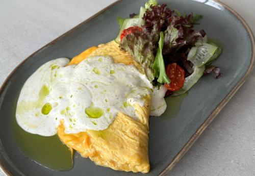 a plate with an omelet with a fried egg and salad at Hotel Boutique TOVMED in Vinnytsya