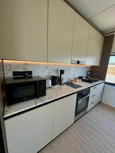 a kitchen with white cabinets and a black microwave at Infinity Residences in Zygi
