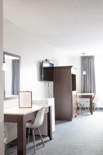 a room with a desk and chairs and a table at Auberge Matha in Saint-Jean-de-Matha