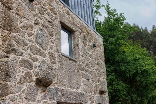 a window on the side of a stone building at Quinta Cerca da Milhera - Unique Experiences by LuxiStay in Ponte da Barca