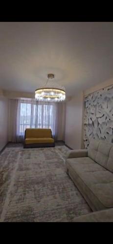 a living room with a couch and a chandelier at Апартамент in Osh