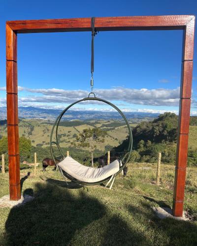 a hammock hanging from a wooden frame with a view at Casa de Vidro na Montanha in Cambuí