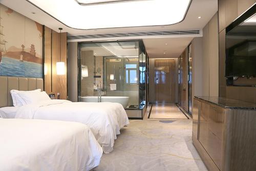 a hotel room with two beds and a tub and a television at 海丝博亚国际酒店会议中心 in Donghai
