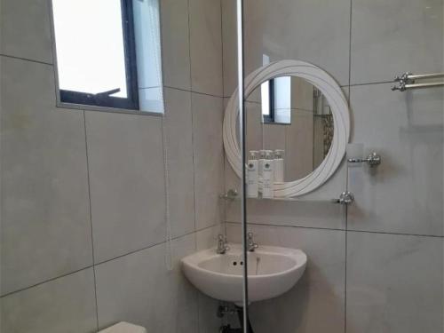 a white bathroom with a sink and a mirror at Rivonia Garden Suites in Johannesburg