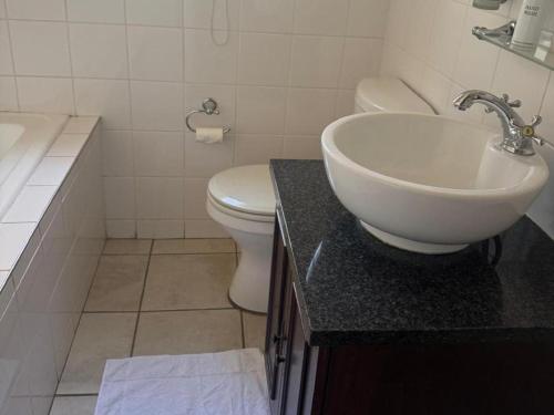 a white bathroom with a sink and a toilet at Rivonia Garden Suites in Johannesburg