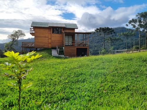 a small wooden house on a hill with a green field at Cabana Araucária in Bom Retiro