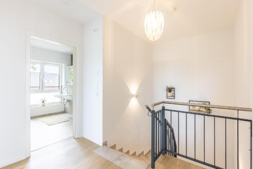 a hallway with white walls and a staircase with a chandelier at Das Strandhaus 2 in Lembruch