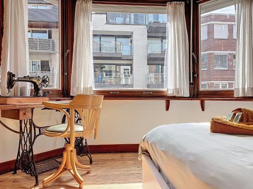 a bedroom with a desk and a bed and windows at Maison Anny Janny - De Panne in De Panne