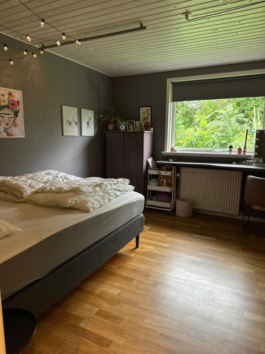 a bedroom with a bed and a large window at Hyggeligt hus i Haderslev med wellness og massage in Haderslev