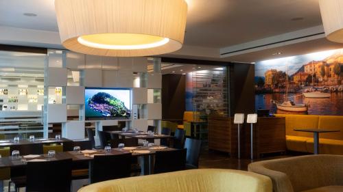 a restaurant with tables and chairs and a flat screen tv at Hotel Cruise in Lucino