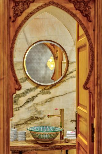 a bathroom with a mirror and a bowl on a counter at Riad AL-Ghazlan Hamam & Spa in Marrakech