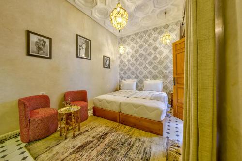 a bedroom with a bed and two chairs and a table at Riad AL-Ghazlan Hamam & Spa in Marrakech