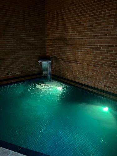 a swimming pool with a water fountain in a brick wall at Status Motel Ourinhos in Ourinhos