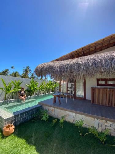 a man sitting on the deck of a house at Villa Mar Milagres - bangalôs de luxo em São Miguel dos Milagres, Alagoas in São Miguel dos Milagres