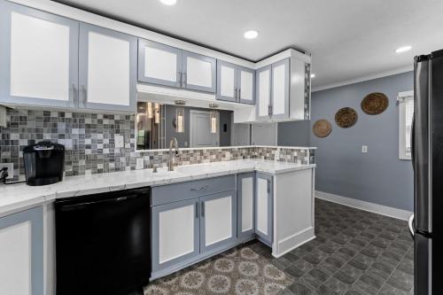 a kitchen with white cabinets and a black refrigerator at Downtown Fun Meets Ultimate Game Night in Muskegon