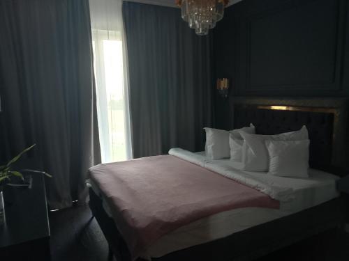 una camera da letto con un letto con cuscini bianchi e una finestra di Exquisite Prima a Oradea