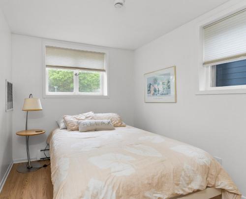 a white bedroom with a bed and two windows at 30 Day Rental - Walking Distance to Grand Haven in Grand Haven