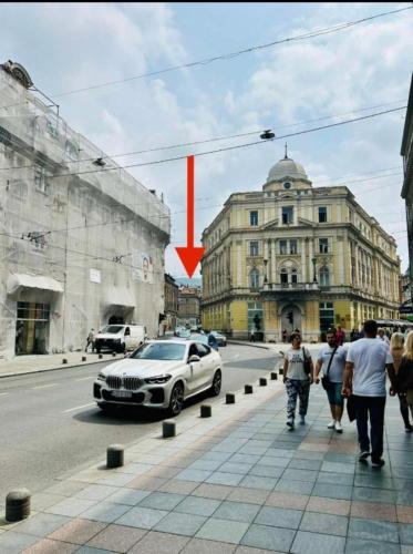 a white car parked on a city street with a red arrow at Apartman Katedrala in Sarajevo