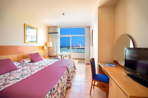a hotel room with a bed and a flat screen tv at Hotel Servigroup Marina Playa in Mojácar