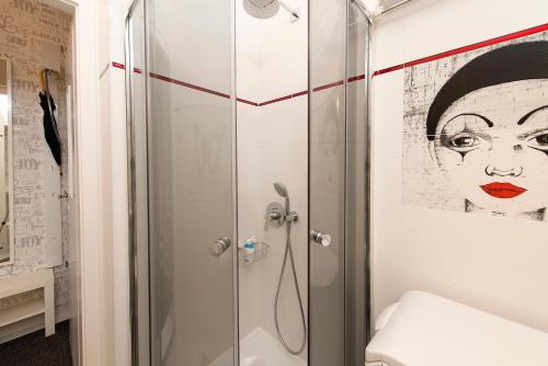 a shower in a bathroom with a painting of a woman at Monroe Central Budapest in Budapest