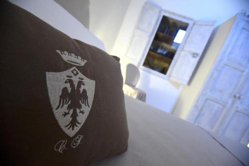 a pillow with a crest on it sitting on a bed at Palazzo Castriota in Alezio