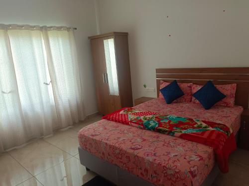 a bedroom with a bed with red sheets and blue pillows at Asprin Homestay in Munnar