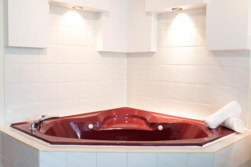 a red bath tub in a white tiled bathroom at Auberge Matha in Saint-Jean-de-Matha