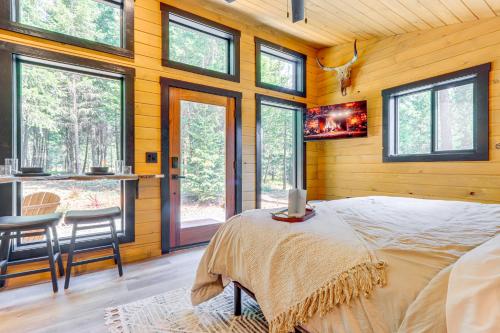 a bedroom with a bed in a room with windows at 8 Mi to Farragut State Park Wooded Cabin Escape! in Athol