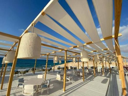 a deck with chairs and tables on the beach at Chalet El-Assar - Mountain View Ras El-Hekma in Ras Elhekma