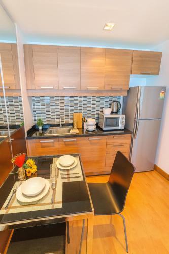 a kitchen with a glass table and a stainless steel refrigerator at Great Balcony with 2 Beds Executive Unit in Bangkok