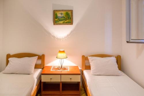 two beds in a room with a lamp on a table at City Apartments Gosposhtina in Budva