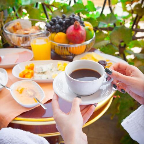 een persoon met een kopje koffie op een tafel met fruit bij Chalé dos Ventos in Amontada