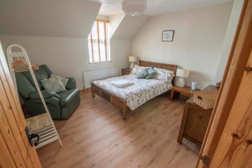 a bedroom with a bed and a couch and a chair at Corner Cottage in Castlerock