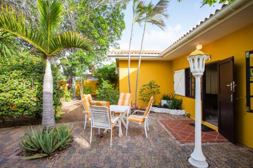 a patio with a table and chairs and a yellow house at Villa Seaside Boca Sami in Sint Michiel