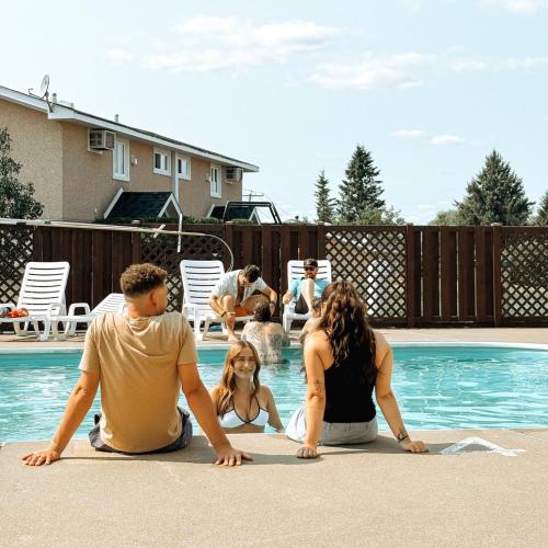 a group of people sitting around a swimming pool at Auberge Matha in Saint-Jean-de-Matha