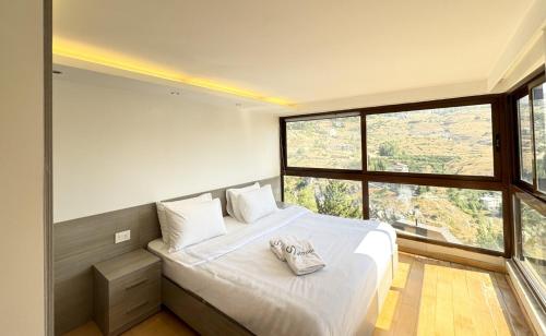 a bedroom with a white bed with a large window at Amelia Duplex 3-BR in Faraya in Fārayyā