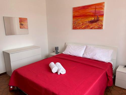 a bedroom with a red bed with two white towels on it at Villa la Gravina in Statte