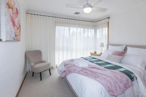 Un dormitorio con una cama y una silla y una ventana. en Stylish 3BR Walk to Town, en Trentham
