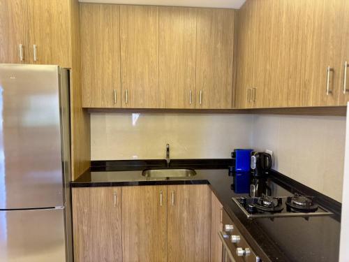 a kitchen with wooden cabinets and a stainless steel refrigerator at Sapa - 2-BR w Terrace in Faraya in Fārayyā