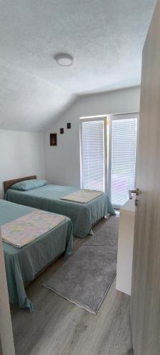 two beds in a room with two windows at Vila Đul in Konjic