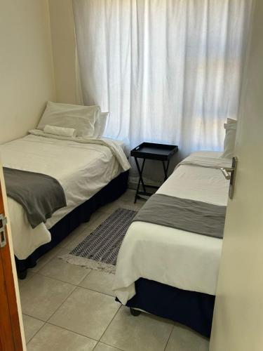 two beds in a room with a window at MV self-catering 3 Units in Bloemfontein