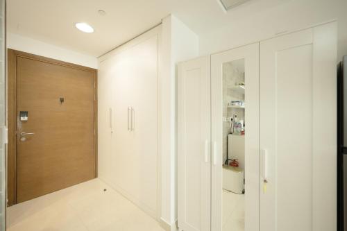 a hallway with white walls and a wooden door at Studio Apartment - Yas Adventure by M in Abu Dhabi